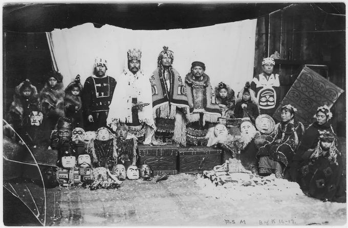 Northwest Coast chiefs and shamans in ceremonial regalia with masks and bentwood boxes.