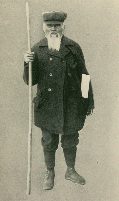 Arthur Wellington Clah, Tsimshian diarist, standing with a walking staff and his journal papers.