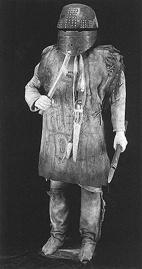 A Haida warrior in a carved wooden helmet and hide armor, holding a dagger.